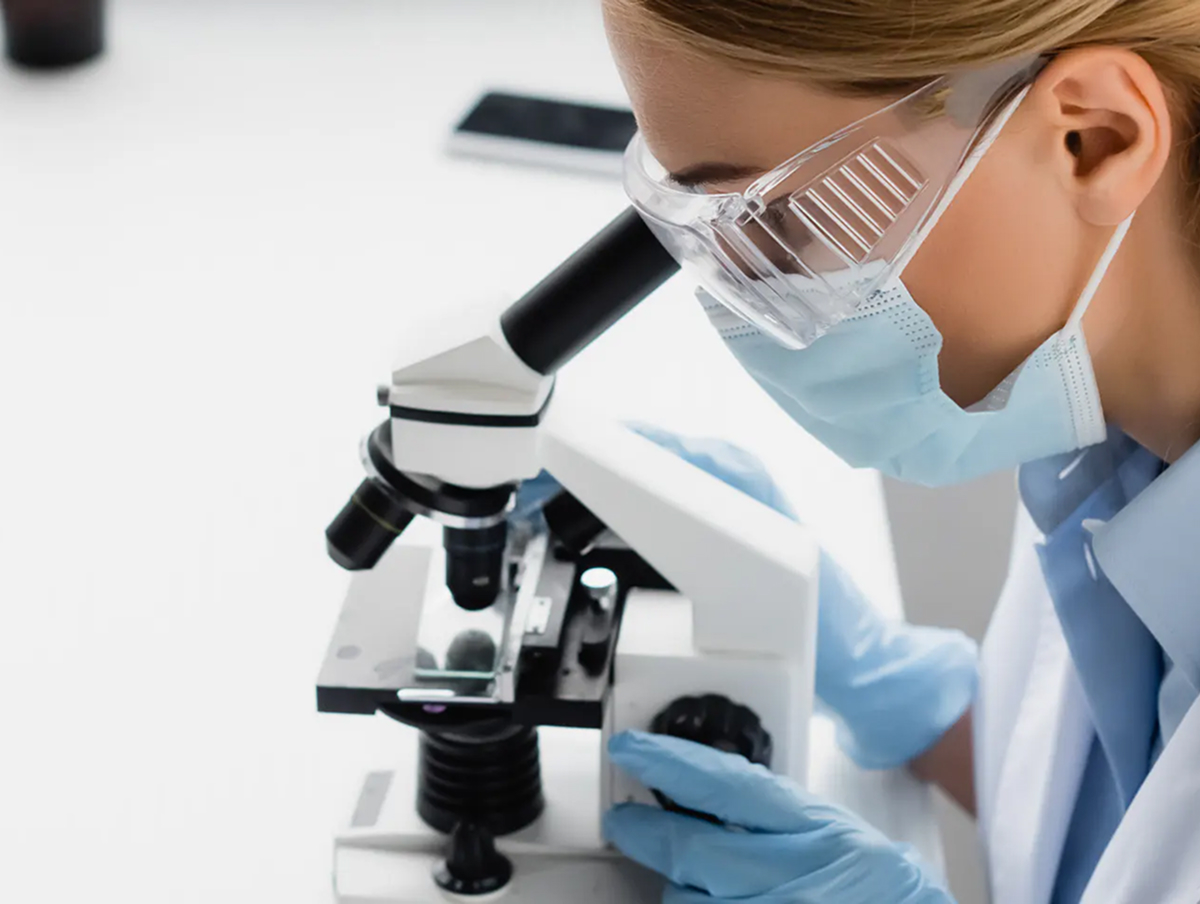 Pharmaceutical manufacturing technician looking at a sample through a microscope