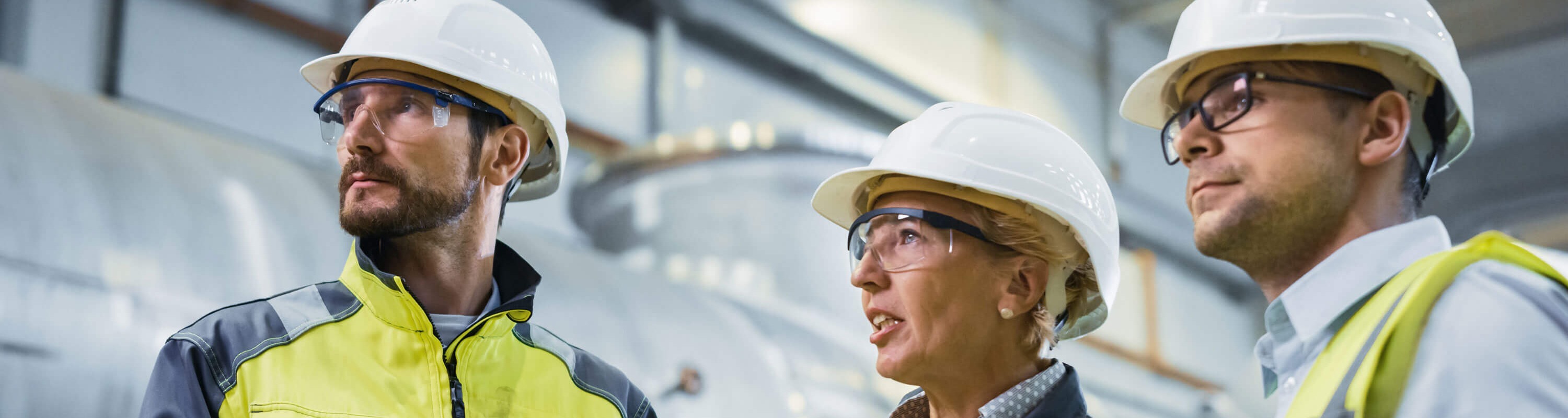 Two oil rig workers in yellow high-vis jackets and white hard hats talking to a filtration supplier