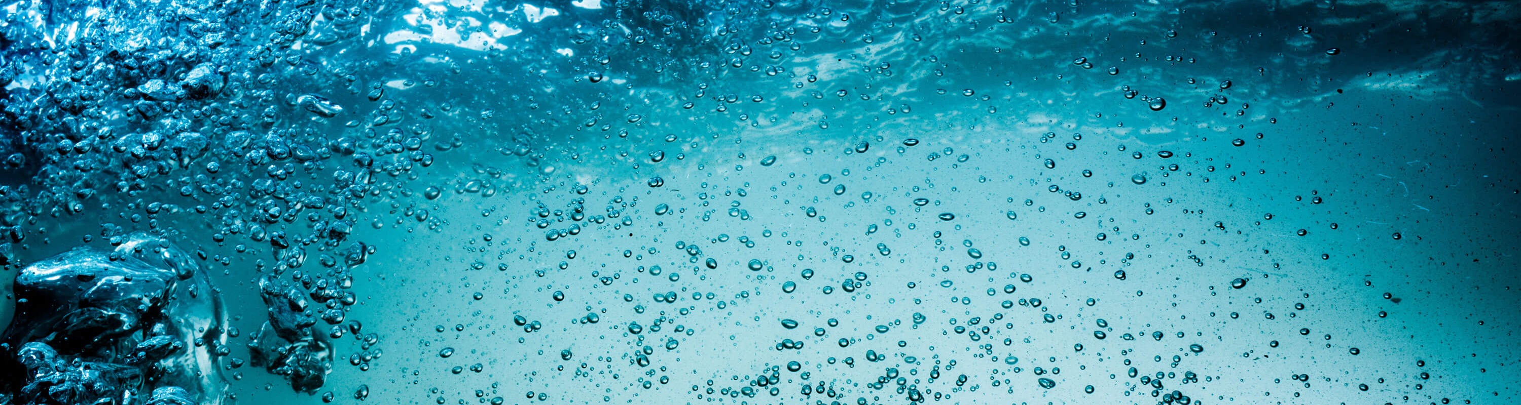 Shot of the ocean just below the surface, with numerous bubbles of different shapes and sizes rising to the top