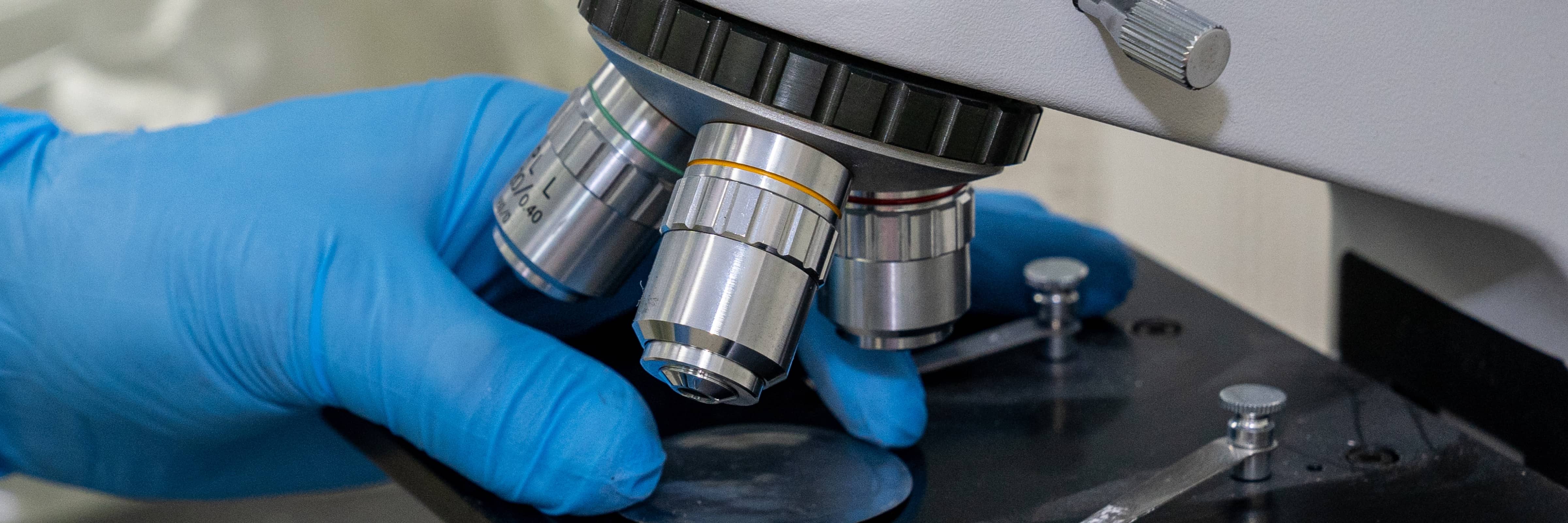 Worker at a pharmaceutical manufacturing plant using a microscope