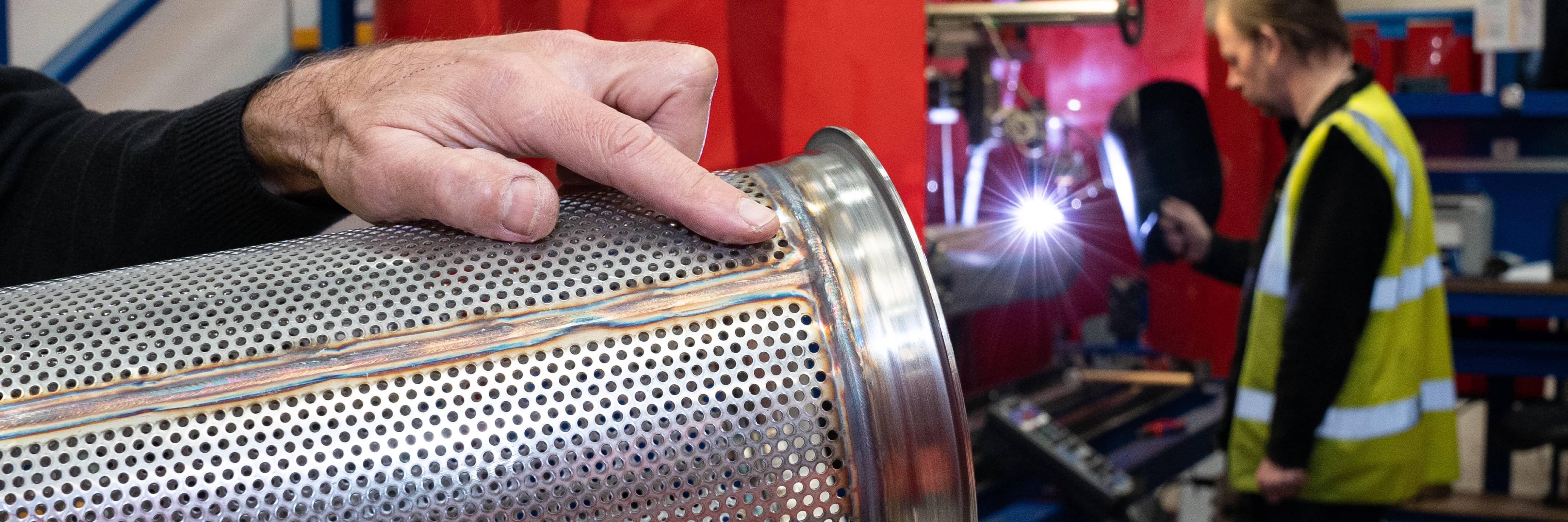 Worker at a manufacturing facility investigating a machine component for damage