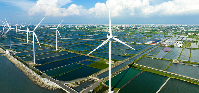 Wind turbines in field by road and water